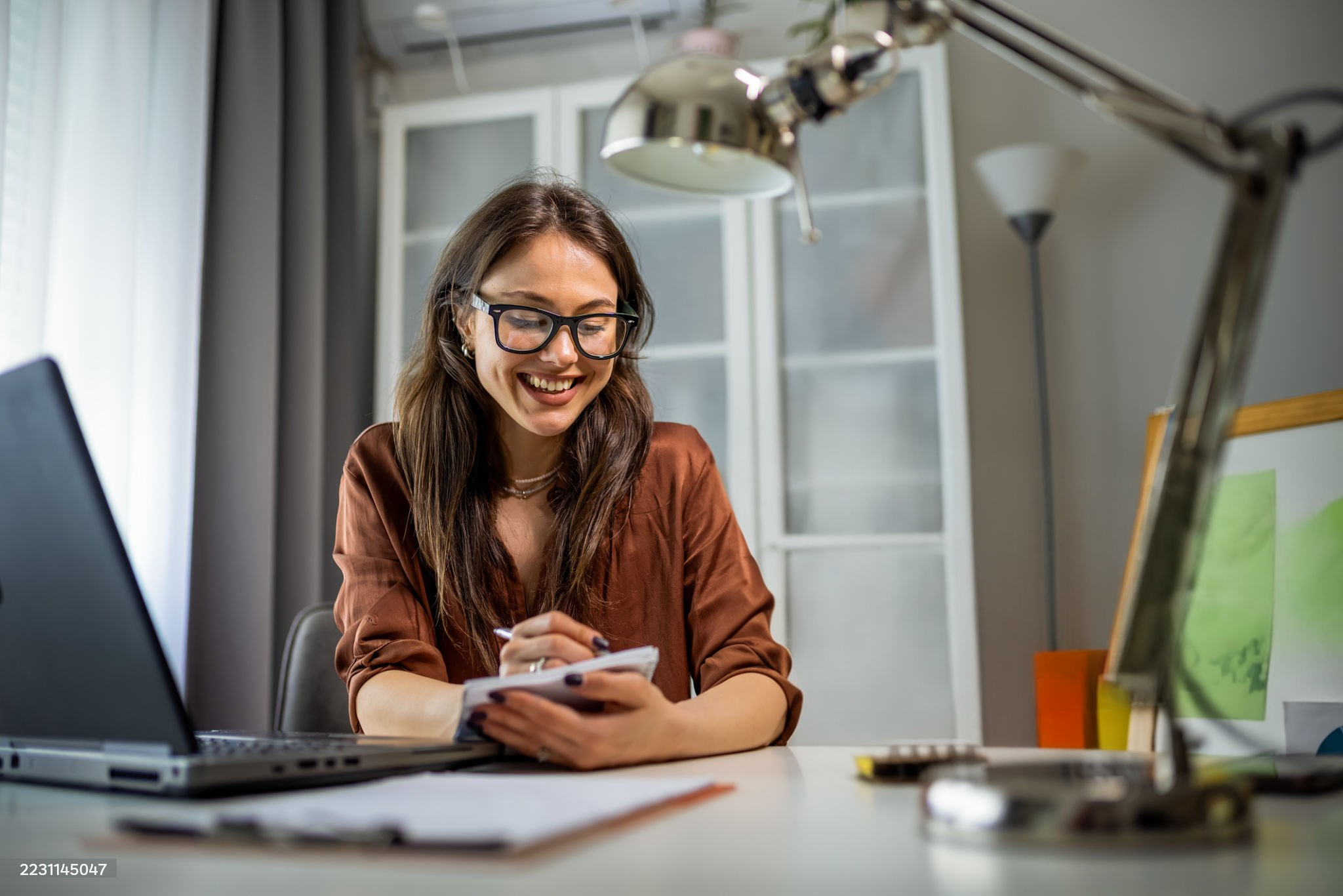 Smiling professional writing in a notebook at her desk
